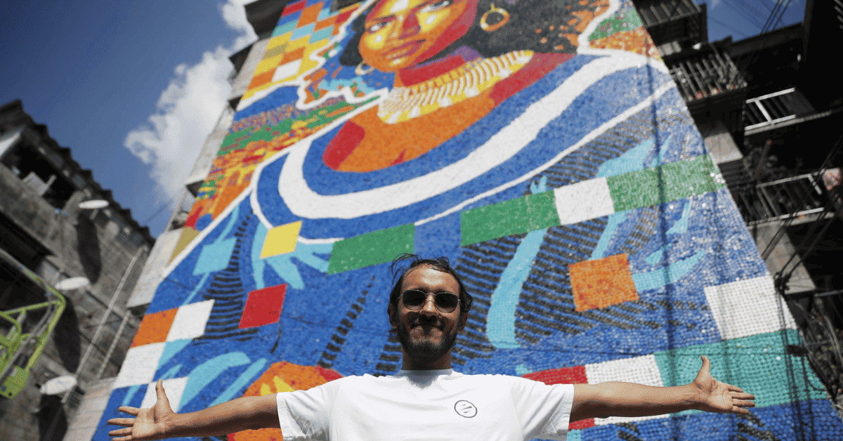 El artista Óscar Olivares con su mural de tapas en San Salvador.