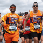 Dos hombres corriendo con la camiseta naranja de la fundación Children With Cancer.