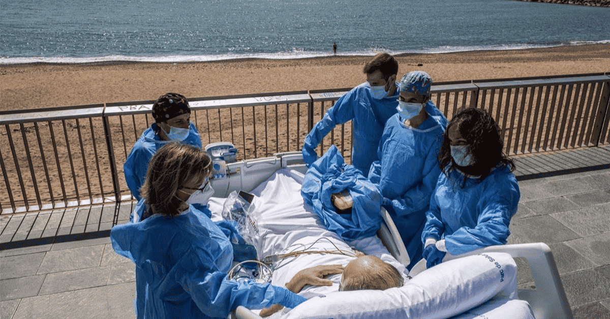 Paciente en camilla rodeado de médicos y enfermeras mientras observa el mar.