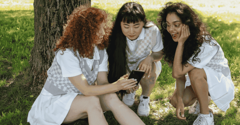 Tres adolescentes obserdando el móvil.