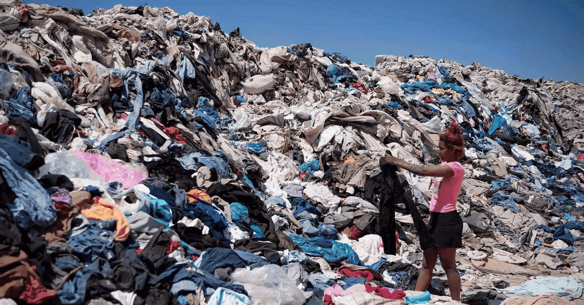 Una mujer con una prenda textil en sus manos en un vertedero de desechos textiles