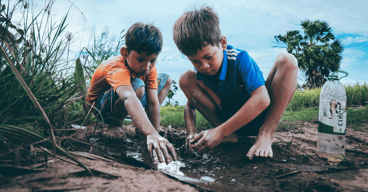 Dos niños jugando en un charco de barro.