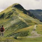 Montaña verde y personas practicando senderismo
